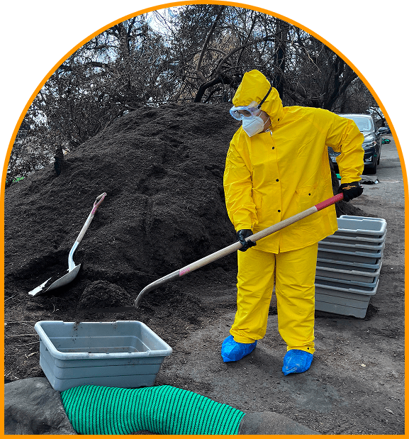A person in yellow suit and blue boots holding a shovel.