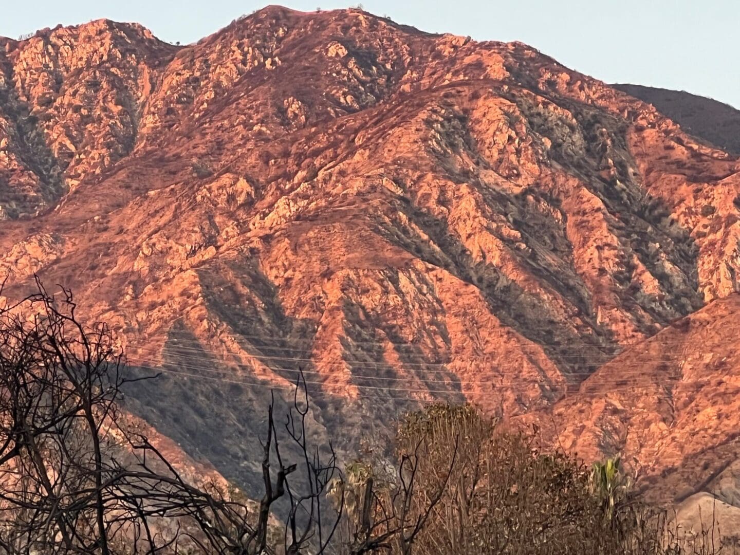 A mountain with red rocks and trees in the foreground.
